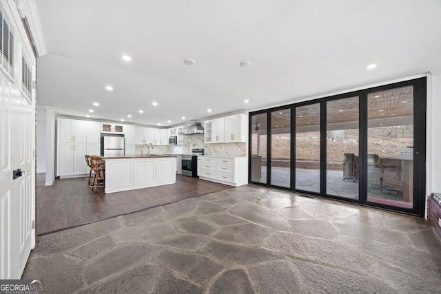 kitchen with white cabinetry, fridge, a kitchen island, stainless steel range with electric cooktop, and wall chimney exhaust hood