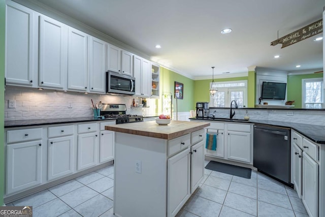 kitchen with pendant lighting, sink, white cabinets, light tile patterned floors, and stainless steel appliances