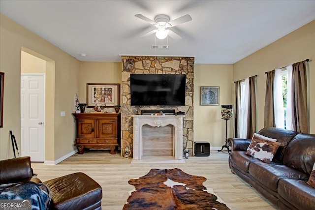 living room with ceiling fan, a fireplace, and light wood-type flooring