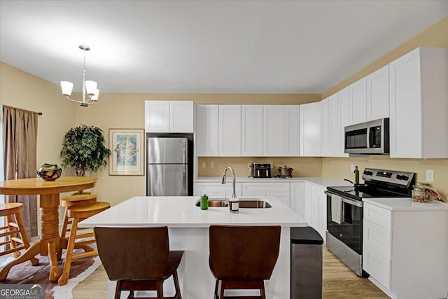 kitchen with sink, decorative light fixtures, stainless steel appliances, and white cabinets