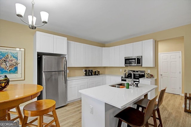 kitchen featuring sink, white cabinetry, decorative light fixtures, an island with sink, and stainless steel appliances