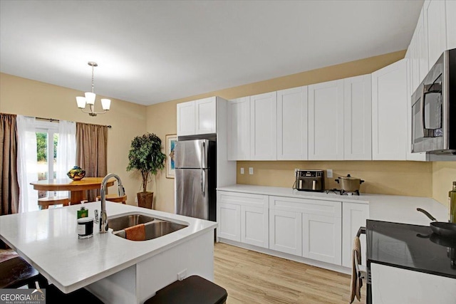 kitchen with sink, white cabinetry, appliances with stainless steel finishes, an island with sink, and pendant lighting