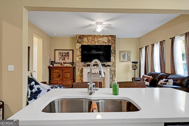 kitchen featuring ceiling fan, light stone countertops, and sink