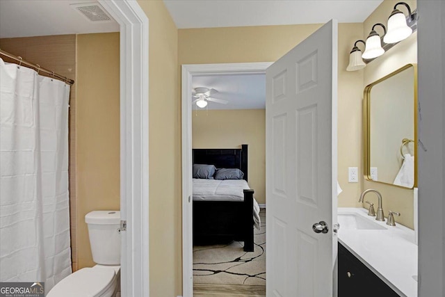 bathroom with hardwood / wood-style flooring, vanity, ceiling fan, and toilet