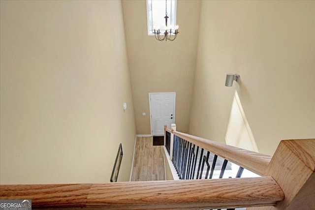 staircase with hardwood / wood-style flooring and an inviting chandelier