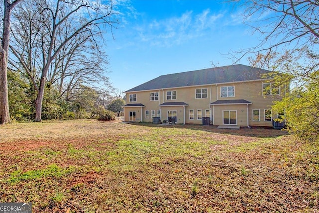 rear view of property with central AC and a lawn