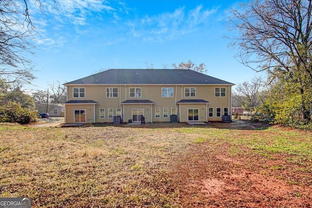 rear view of house featuring cooling unit and a yard