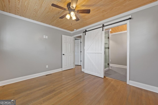 unfurnished bedroom featuring crown molding, wood-type flooring, a barn door, and wooden ceiling