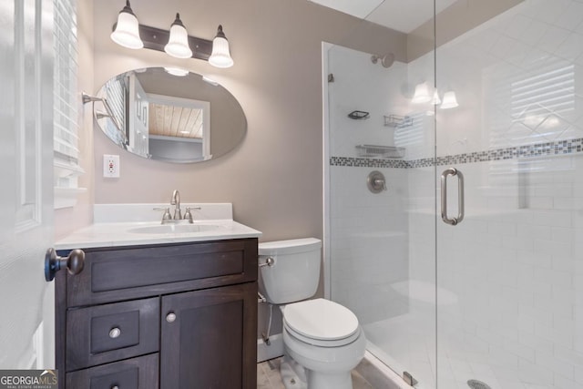 bathroom with vanity, a shower with door, and toilet