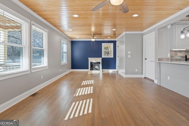 unfurnished living room featuring ornamental molding, wood-type flooring, wooden ceiling, and ceiling fan