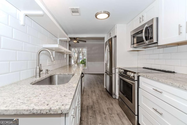 kitchen featuring wood-type flooring, sink, white cabinets, light stone counters, and stainless steel appliances