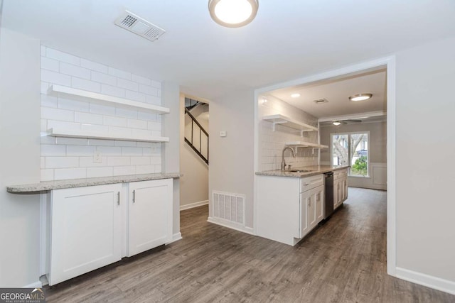 kitchen with tasteful backsplash, white cabinetry, dishwasher, light stone counters, and dark wood-type flooring