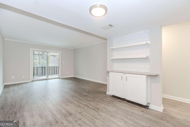 unfurnished living room with ornamental molding and light wood-type flooring