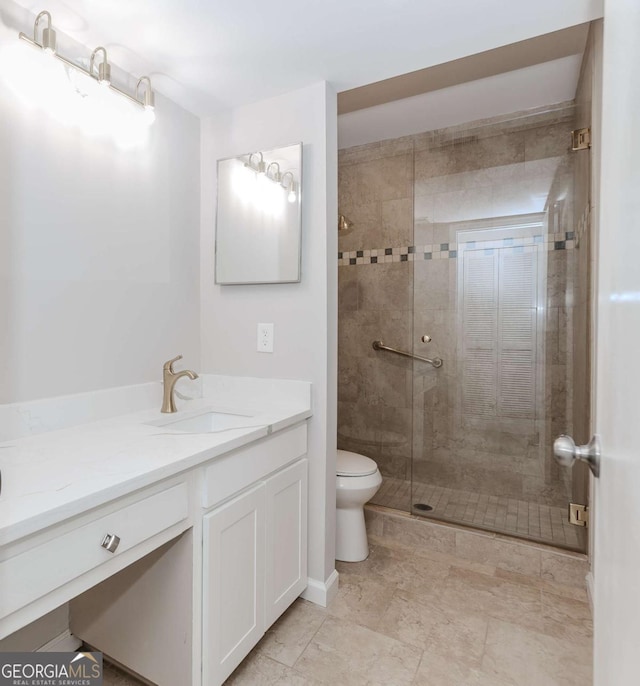 bathroom with vanity, a shower with door, and toilet