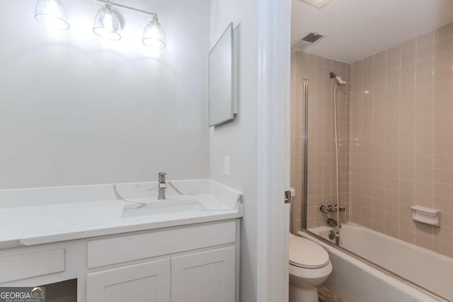 full bathroom featuring tiled shower / bath, vanity, and toilet