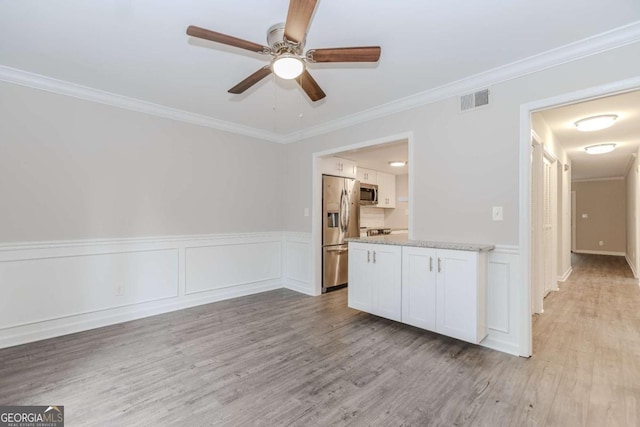 interior space featuring stainless steel appliances, crown molding, and white cabinets