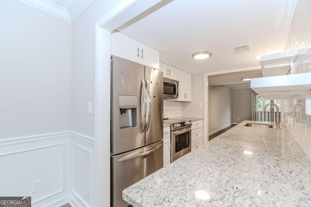 kitchen featuring light stone counters, sink, white cabinets, and appliances with stainless steel finishes