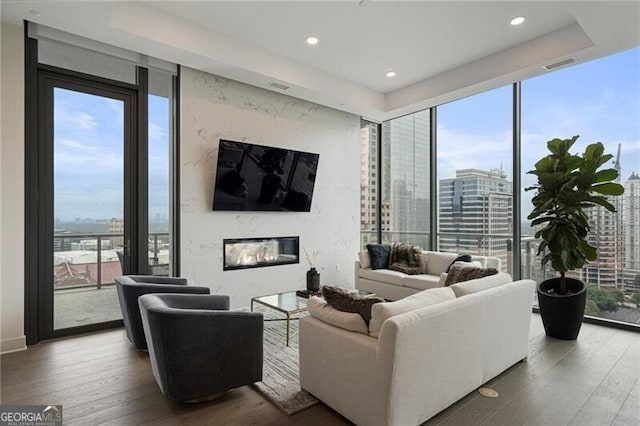 living room featuring a premium fireplace, wood-type flooring, and expansive windows