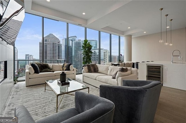 living room with sink, wood-type flooring, expansive windows, a raised ceiling, and beverage cooler