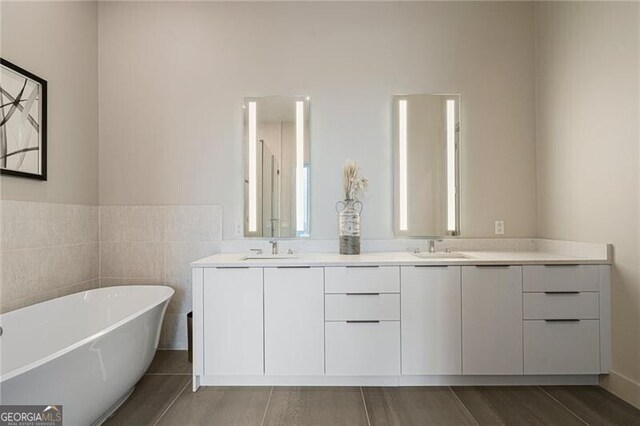 bathroom with vanity, tile walls, and a tub