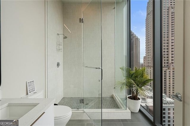 bathroom featuring vanity, toilet, an enclosed shower, and tile patterned flooring