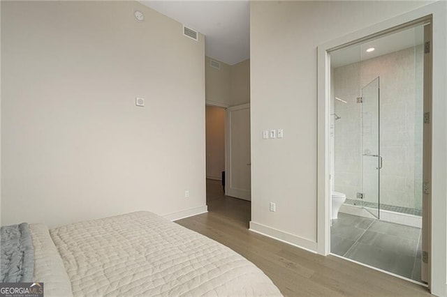 bedroom featuring ensuite bath and hardwood / wood-style floors