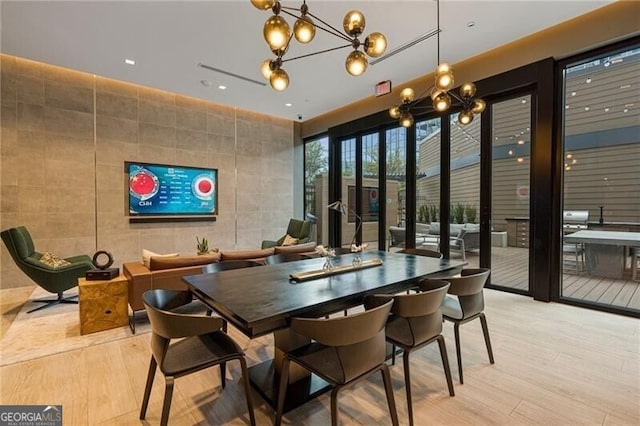 dining space with tile walls, an inviting chandelier, and light wood-type flooring