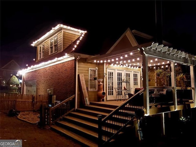 back house at twilight featuring french doors, a deck, and a pergola