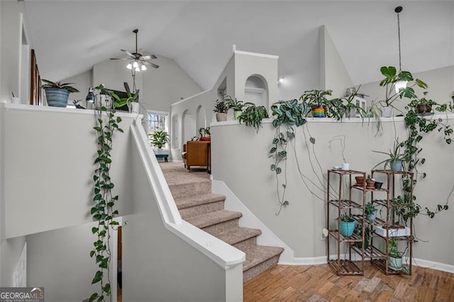 stairs featuring vaulted ceiling, ceiling fan, and hardwood / wood-style floors