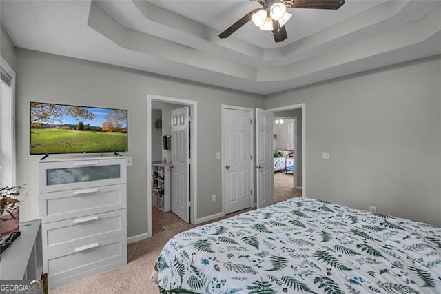 carpeted bedroom featuring a raised ceiling and ceiling fan