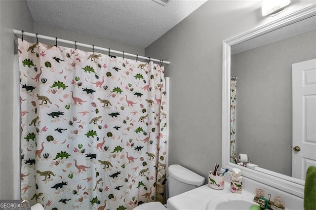 bathroom featuring vanity, a shower with curtain, toilet, and a textured ceiling