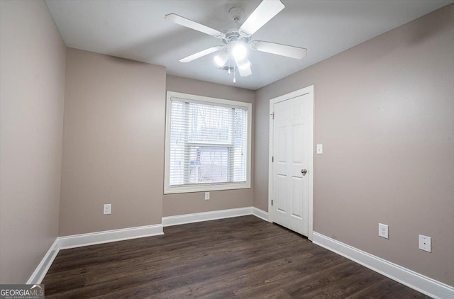 spare room featuring a ceiling fan, baseboards, and dark wood-style flooring