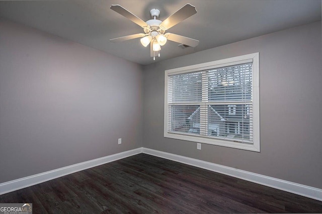 empty room with dark wood-style floors, ceiling fan, visible vents, and baseboards