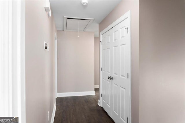 hallway with dark wood-type flooring, attic access, and baseboards