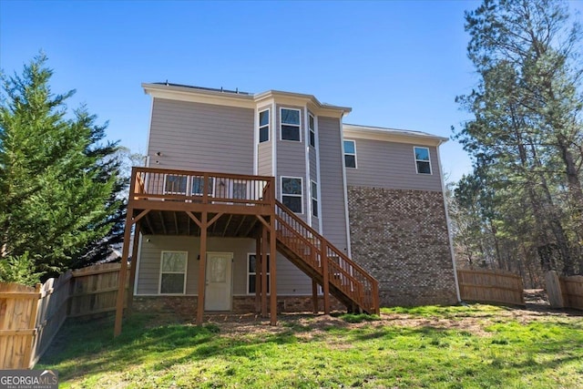 rear view of house featuring a fenced backyard, stairway, a deck, and a lawn