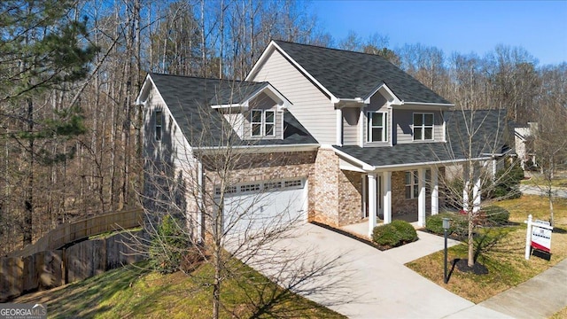 traditional-style house with a shingled roof, concrete driveway, and brick siding