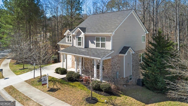 traditional home with a garage, concrete driveway, a front lawn, and central air condition unit