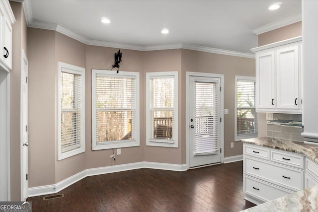 unfurnished dining area featuring baseboards, visible vents, dark wood finished floors, and crown molding