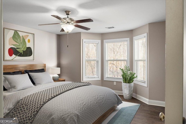 bedroom featuring a ceiling fan, visible vents, dark wood finished floors, and baseboards