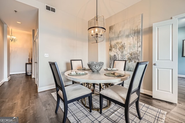 dining area featuring dark wood-type flooring and an inviting chandelier