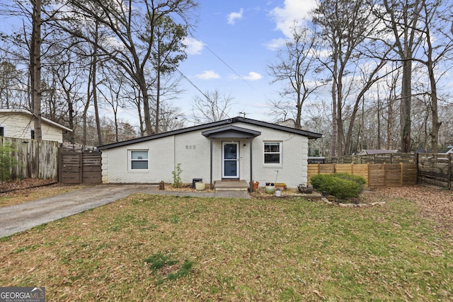 view of front of house with driveway, fence, a front lawn, and brick siding