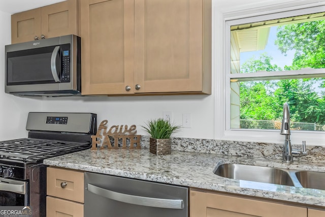 kitchen with sink, stainless steel appliances, and light stone countertops