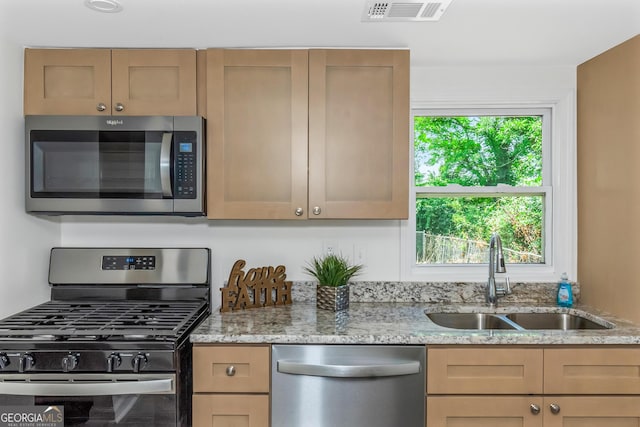 kitchen featuring appliances with stainless steel finishes, sink, and light stone counters