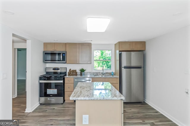 kitchen featuring a kitchen island, wood-type flooring, sink, light stone counters, and stainless steel appliances