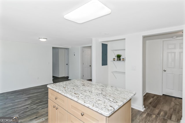 kitchen with light stone countertops, dark hardwood / wood-style flooring, a center island, and light brown cabinetry