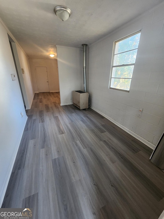 unfurnished living room featuring hardwood / wood-style flooring, a textured ceiling, and a wood stove