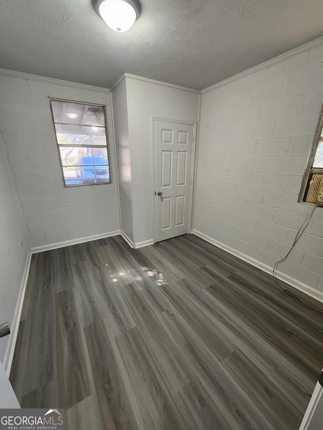 unfurnished room with crown molding, dark wood-type flooring, and a textured ceiling