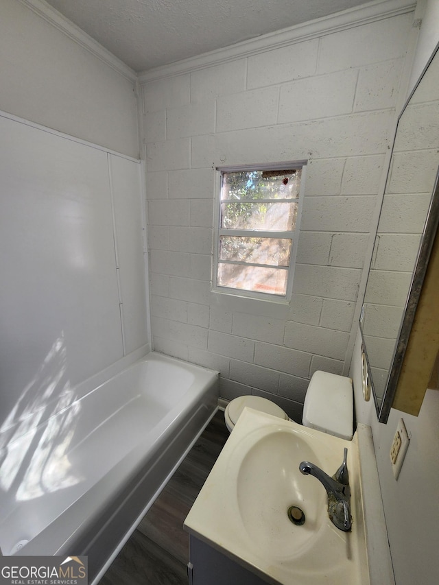 bathroom featuring hardwood / wood-style flooring, a bathtub, vanity, ornamental molding, and toilet