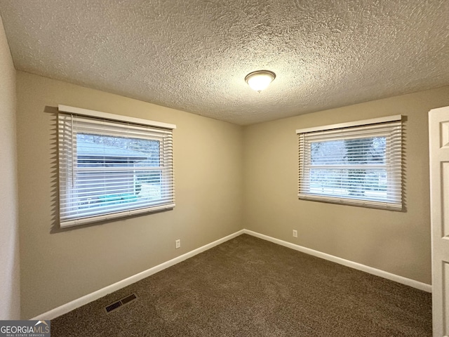 carpeted empty room featuring a textured ceiling