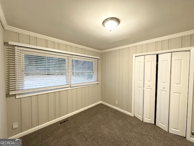 unfurnished bedroom with crown molding, a closet, and dark colored carpet